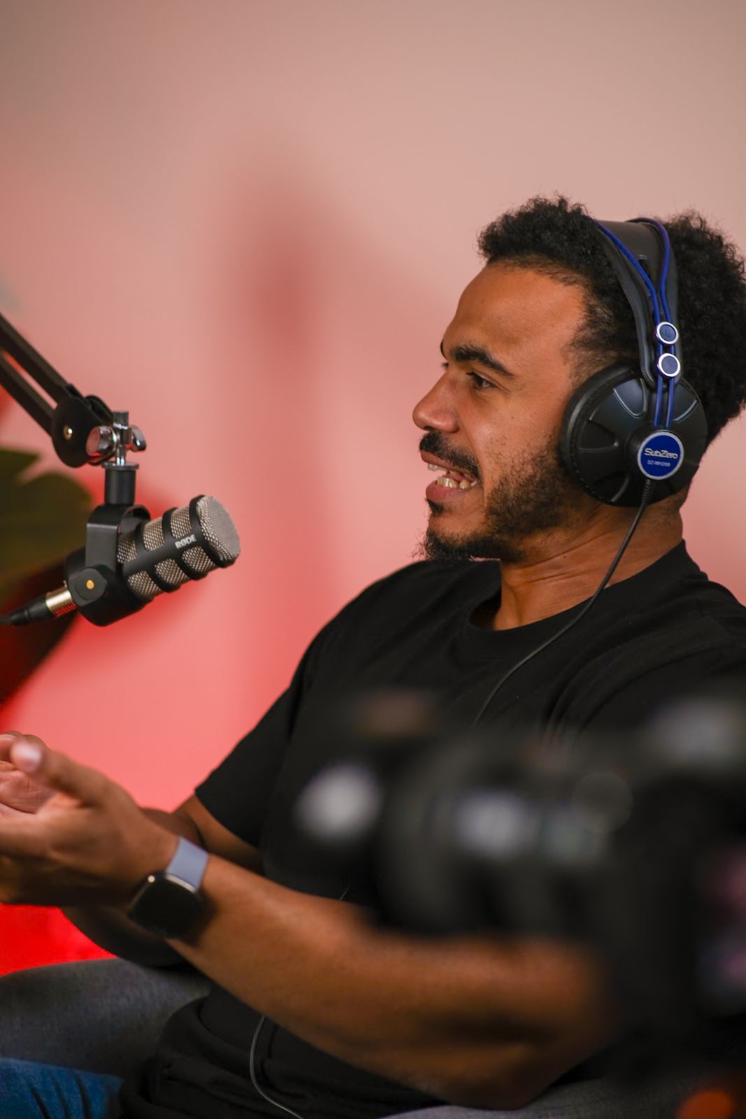 A guest in headphones mid-conversation at the microphone under warm studio lighting